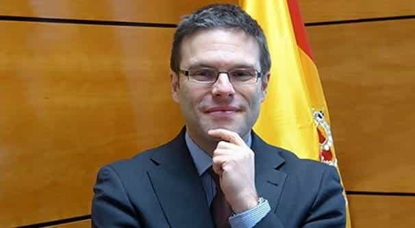 Juan Espinosa stands in an office in front of a Spanish flag.