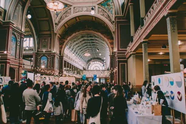 A view of a packed expo hall, with various booths and many attendees.