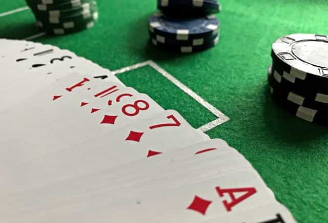 A spread-out deck of cards next to poker chips.