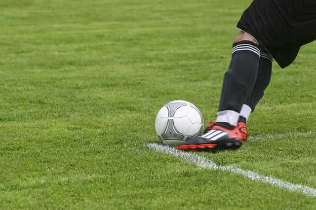 A footballer about to kick a football on a pitch.