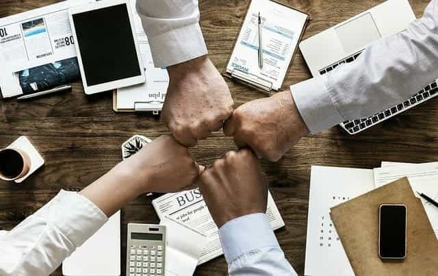 Four closed fists joining together in celebration of a successful agreement.