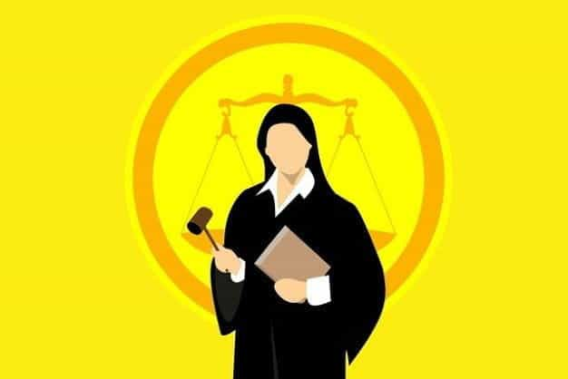 A woman in judge’s robes holding a gavel and a set of documents.