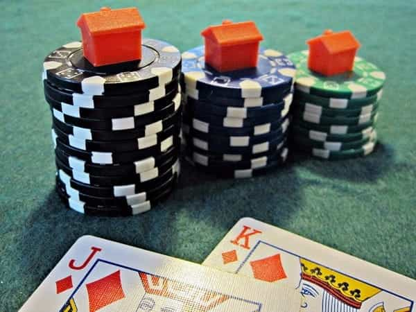 A poker hand, chips and small houses.