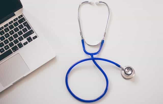 A doctor's stethoscope next to a laptop.