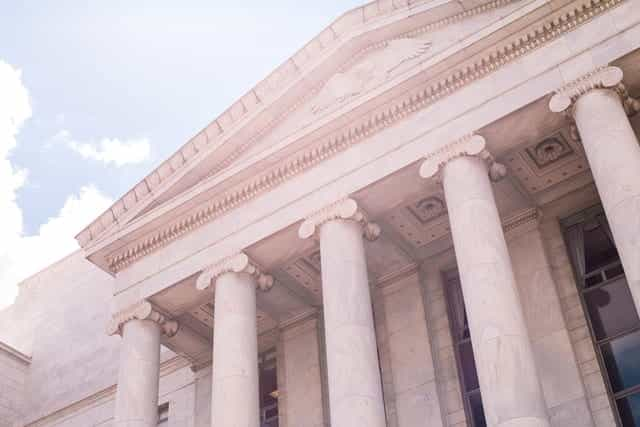 A white, concrete government building with pillars.