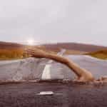 A swimmer swimming through a paved, empty road.