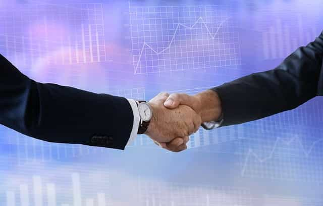 Two peoples’ arms in business suits shaking hands.