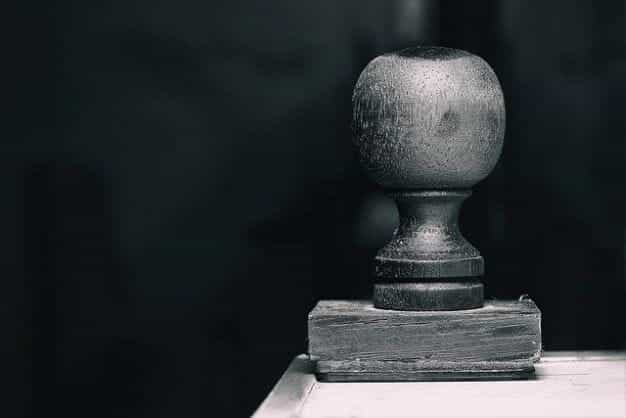 A large wooden stamp resting on its face on the corner of a table.