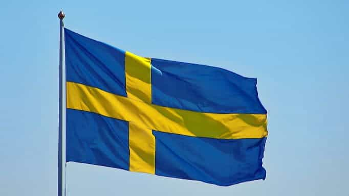 A flag of Sweden against a bright blue sky during the day.