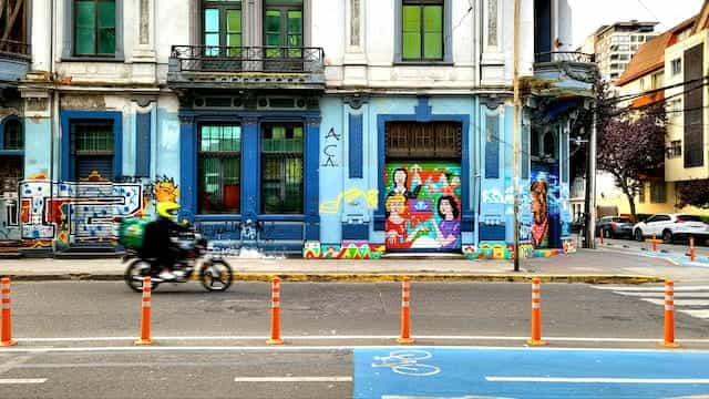 A motorbike delivery person rides past a graffiti-covered wall in Concepcion, Chile.