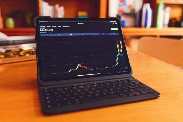 An upwards trending candlestick chart on a laptop screen.