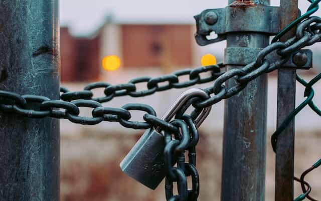 A heavy lock and chain keep a gate closed.