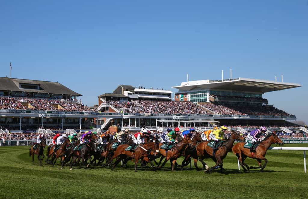 A general view of horses and riders taking the first bend at Aintree Racecourse.