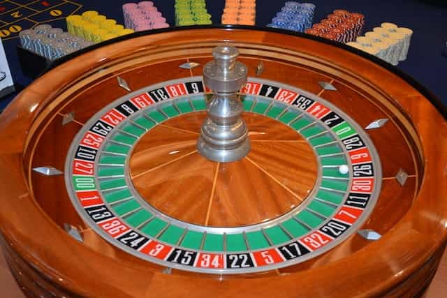 A roulette wheel surrounded by colorful betting chips.