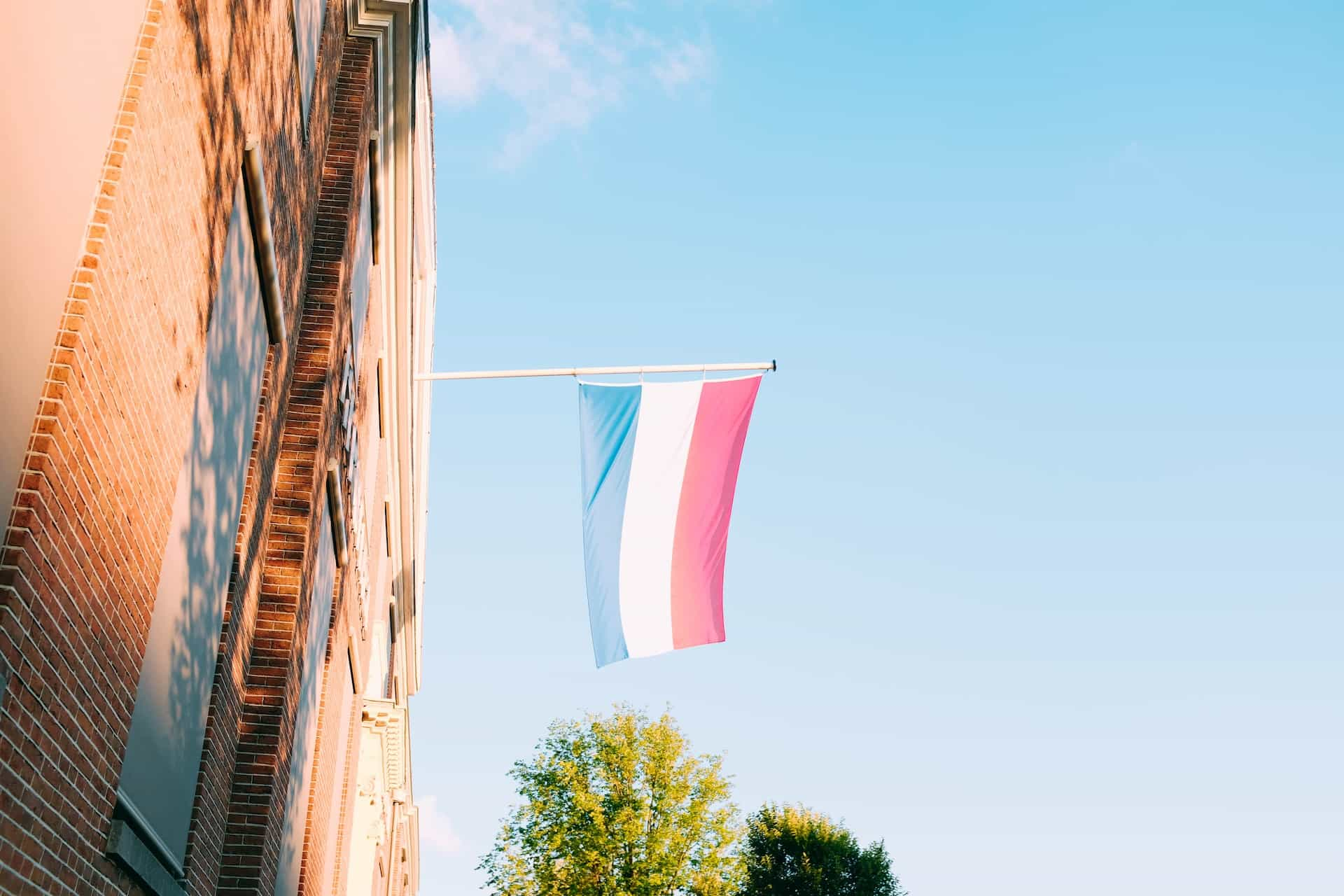 A red, white, and blue flag hoisted out of a window.