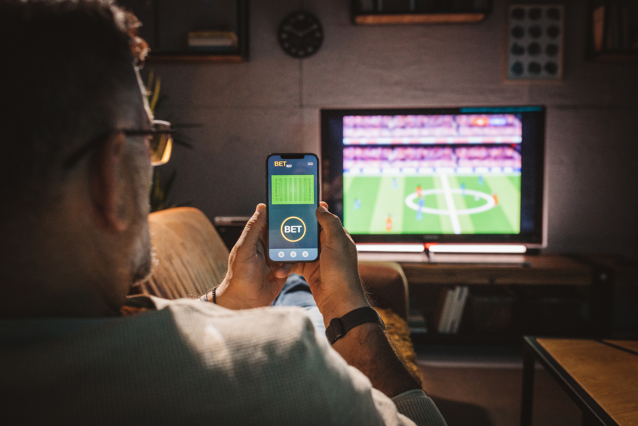 An image of someone watching TV whilst viewing a betting app